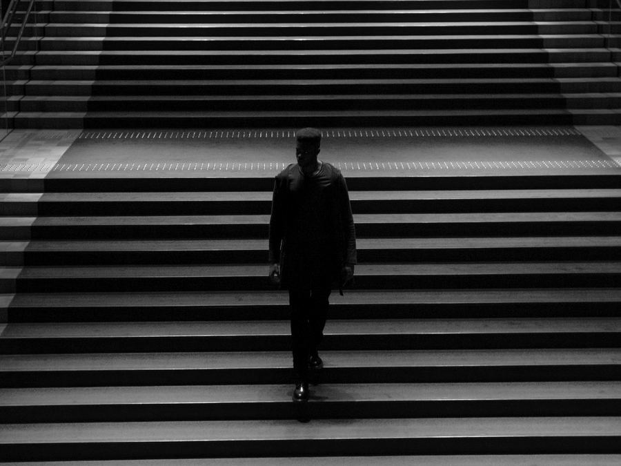 A figure walking up a red-carpet staircase